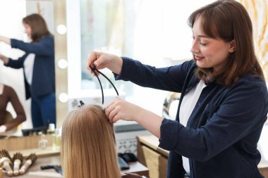 Profesyonel kuaför müşteriyle kuaförde çalışıyor.
