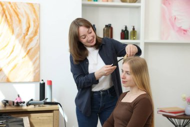 Profesyonel kuaför müşteriyle kuaförde çalışıyor.