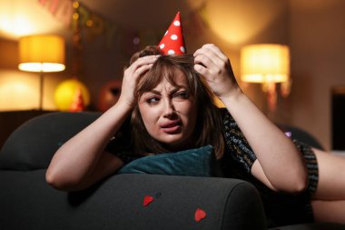 Akşamdan kalma bir kadın partiden sonra dağınık bir odada kanepede yatıyor.