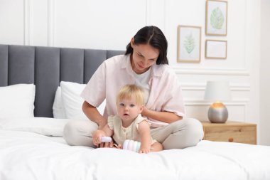 Anne, tatlı kızıyla evde yatakta oynuyor.