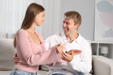 Evdeki koltukta hamilelik testi olan mutlu çift.