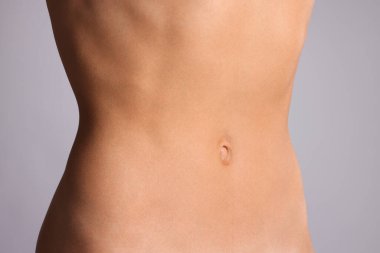 Gri arka planda düz göbekli kadın, yakın plan.