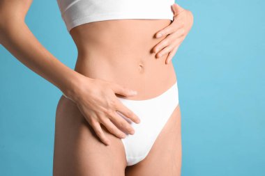 Açık mavi arka planda düz göbekli kadın, yakın plan.