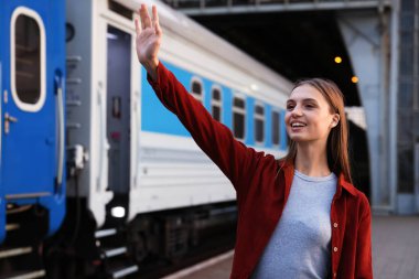 Hoşçakalın. Trenin yanında el sallayan mutlu kadın.