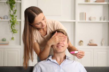 Mutlu genç bir kadın kocasına evde pozitif hamilelik testiyle sürpriz yapıyor.