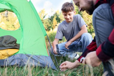 Baba ve oğul kamp çadırı kuruyor, kapatıyorlar.