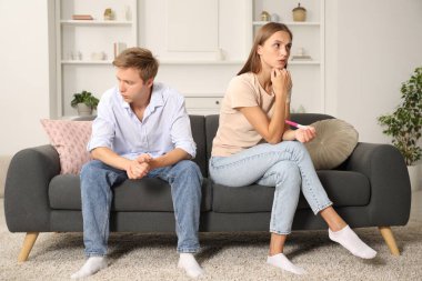 Evdeki koltukta hamilelik testi olan endişeli çift.