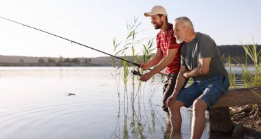 Yaşlı babası ve mutlu oğlu nehirde birlikte balık tutuyorlar.