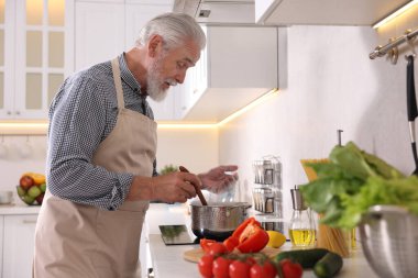 Mutfaktaki mutfağın tepesinde yaşlı bir adam yemek pişiriyor.