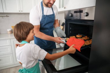 Baba ve oğul fırından hamur işleriyle birlikte yemek tepsisini çıkarıyorlar.