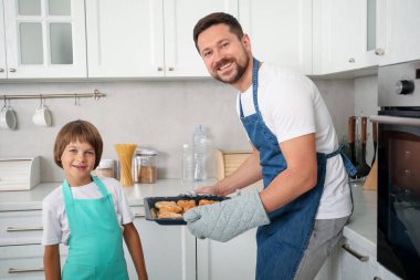 Baba ve oğul mutfakta hamur işi pişiriyor.