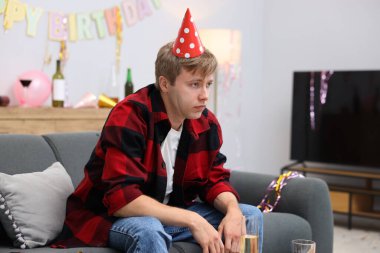 Adam partiden sonra dağınık bir odada kanepede akşamdan kalma.