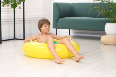 Denizde tatilin hayalini kuruyorum. Evin içinde şişme halkalı küçük çocuk.