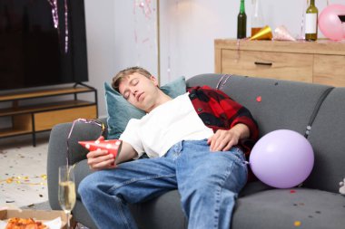 Adam partiden sonra dağınık bir odada kanepede akşamdan kalma.