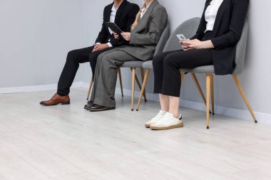 İnsanlar içeride sandalyelerde kuyrukta bekliyor, yakın çekim.