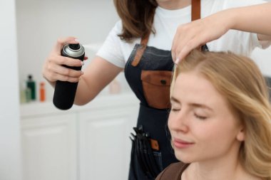 Profesyonel kuaför müşteriyle kuaförde çalışıyor.