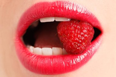 Güzel dudaklı, makyajlı ve ahududulu bir kadın. Yakın plan.