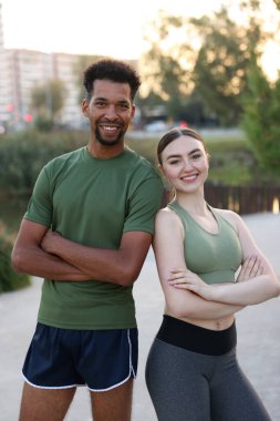 Gülümseyen koşucular dışarıda çapraz kollarla poz veriyorlar.