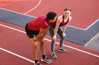 Stadyumda koştuktan sonra dinlenen gülümseyen çift.