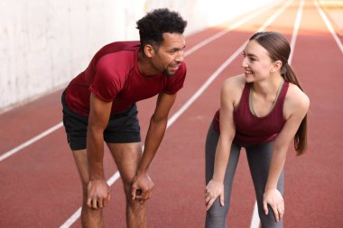 Stadyumda koştuktan sonra dinlenen gülümseyen çift.