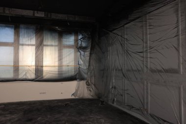 Windows and wall covered with plastic film in empty room