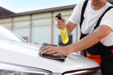 Kaputu gri mikrofiber bez ile silen adam, yakın plan.