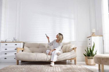 Evdeki klimayı uzaktan kumandayla kontrol eden kadın