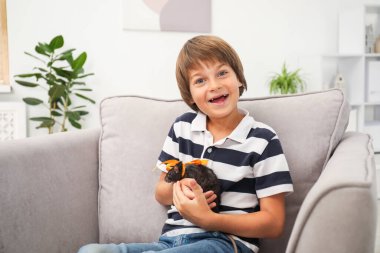 Hayaller gerçek olur. Evdeki koltukta evcil faresi olan mutlu çocuk.
