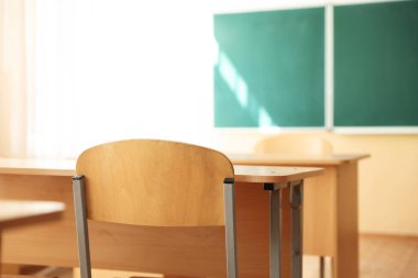 Sınıfta sandalyeli ve yeşil karatahtalı masalar, seçici odaklanma