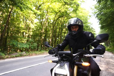 Kasklı genç adam modern motosikleti açık havada kullanıyor. Metin için boşluk