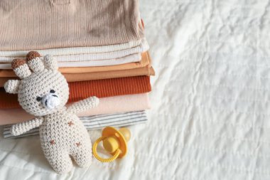 Yatakta temiz bebek kıyafetleri ve aksesuarlar yığını, yakın plan. Metin için boşluk