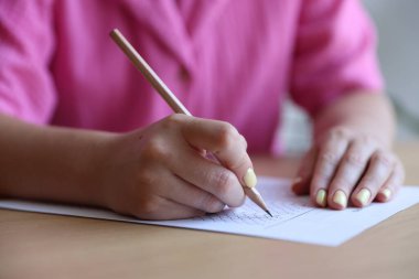 Öğrenci sınıfta çoklu seçim sınavı dolduruyor, yakın çekim. Sınavı geçmek