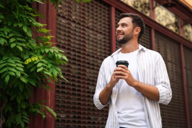Paket kahve. Açık havada kağıt bardak içen bir adam, düşük açılı. Metin için boşluk