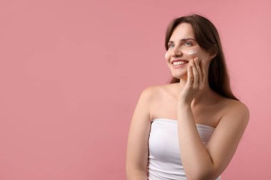 Yüzünde pembe arka planda krem olan güzel bir kadın. Metin için boşluk