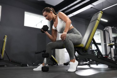 Spor salonunda halterli kadın antrenmanı, düşük açı.