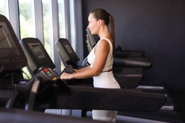 Spor salonunda koşu bandında antrenman yapan atletik kadın.