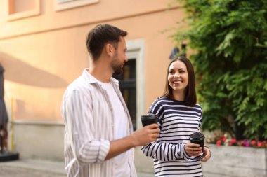 Paket kahve. Kağıt bardaklı bir çift şehirde yürüyor.