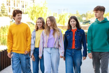 Şehir caddesinde yürüyen bir grup genç.