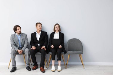 İnsanlar içeride sandalyede kuyrukta bekliyorlar.