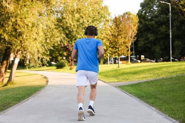 Güneşli bir günde parkta koşan bir adam.