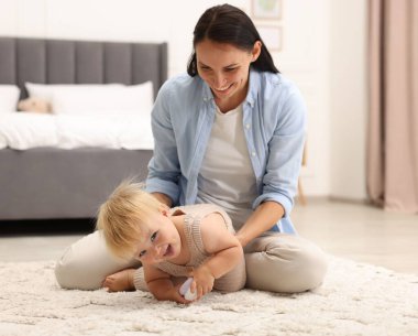 Güzel bebeğiyle gülümseyen anne yatak odasında yerde.
