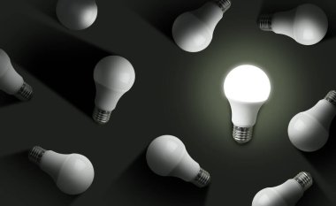 Fikir kavramı. Siyah arka planda diğerleriyle birlikte parlayan bir ampul, üst manzara. Pankart tasarımı