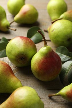 Taze armutlar ve ahşap masada yeşil yapraklar, yakın plan.