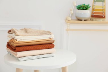 İçerideki beyaz masaya temiz bebek kıyafetleri yığını. Mesaj için yer.