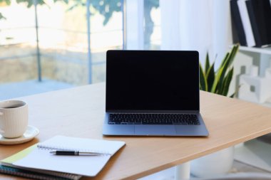 Ev çalışma alanı. Modern laptop ve kırtasiye malzemeleri ahşap masa içinde.