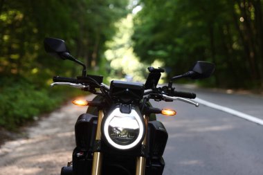 Modern siyah motosiklet açık yolda park edilmiş.