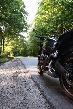 Modern siyah motosiklet açık yolda park edilmiş.