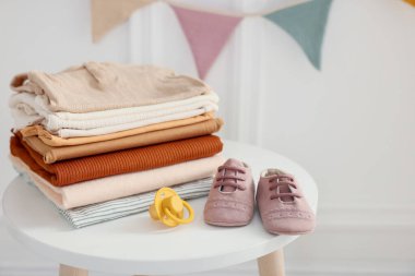 Temiz bebek kıyafetleri ve aksesuarlar beyaz masa içinde, yakın plan.