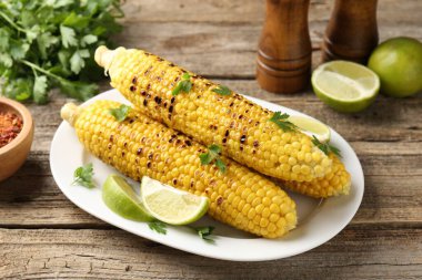 Maydanozlu mısır koçanları ve ahşap masada limon dilimleri, yakın plan.