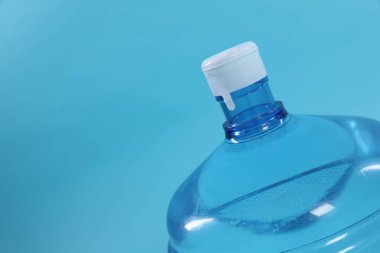 Açık mavi arka planda su bulunan soğutucu şişesi, yakın plan. Metin için boşluk